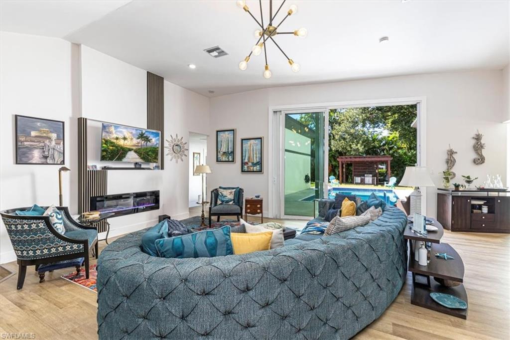 Living room with light wood-style floors, a chandelier, and recessed lighting