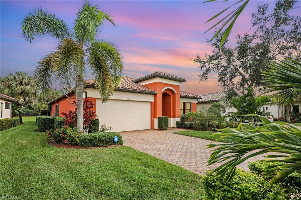 Mediterranean / spanish-style home featuring an attached garage, stucco siding, decorative driveway, a tiled roof, and a lawn