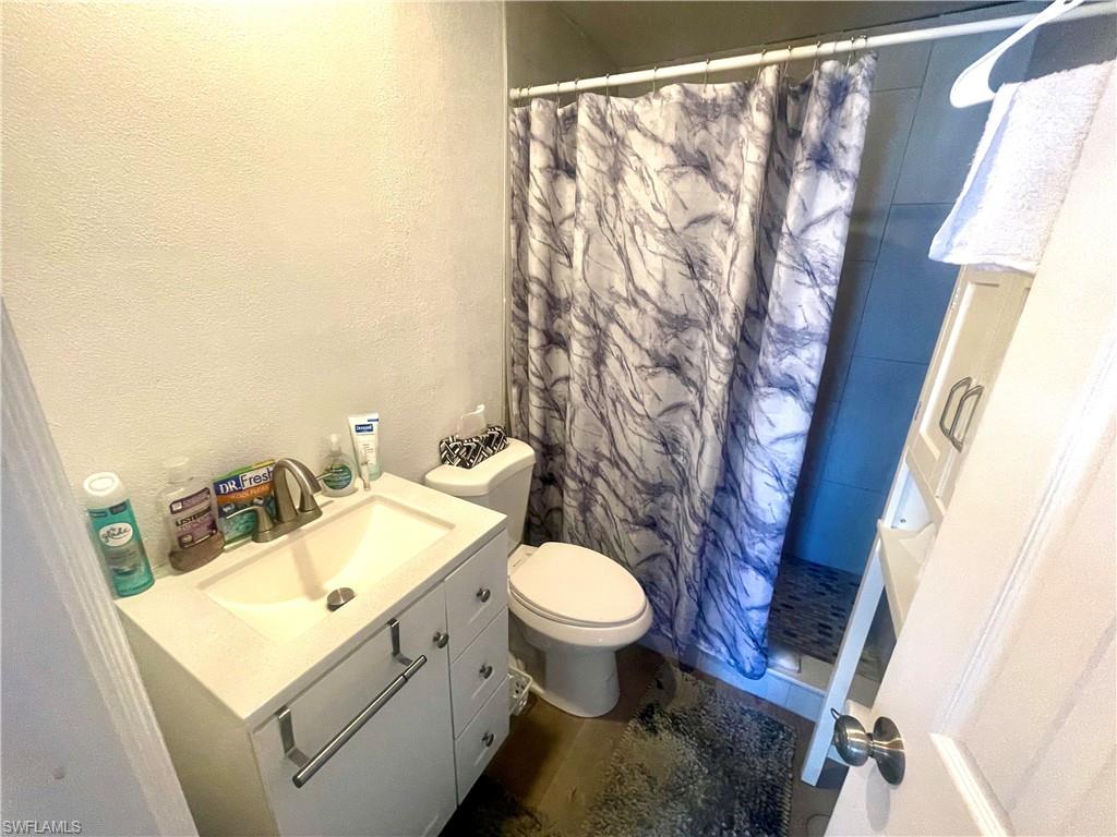 Full bath with vanity, a shower stall, and a textured wall