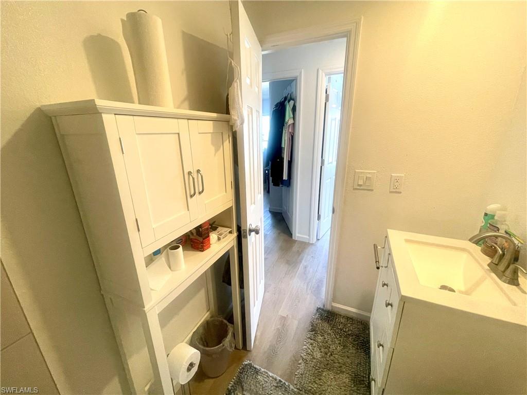 Bathroom with vanity, a textured wall, and dark wood-style flooring