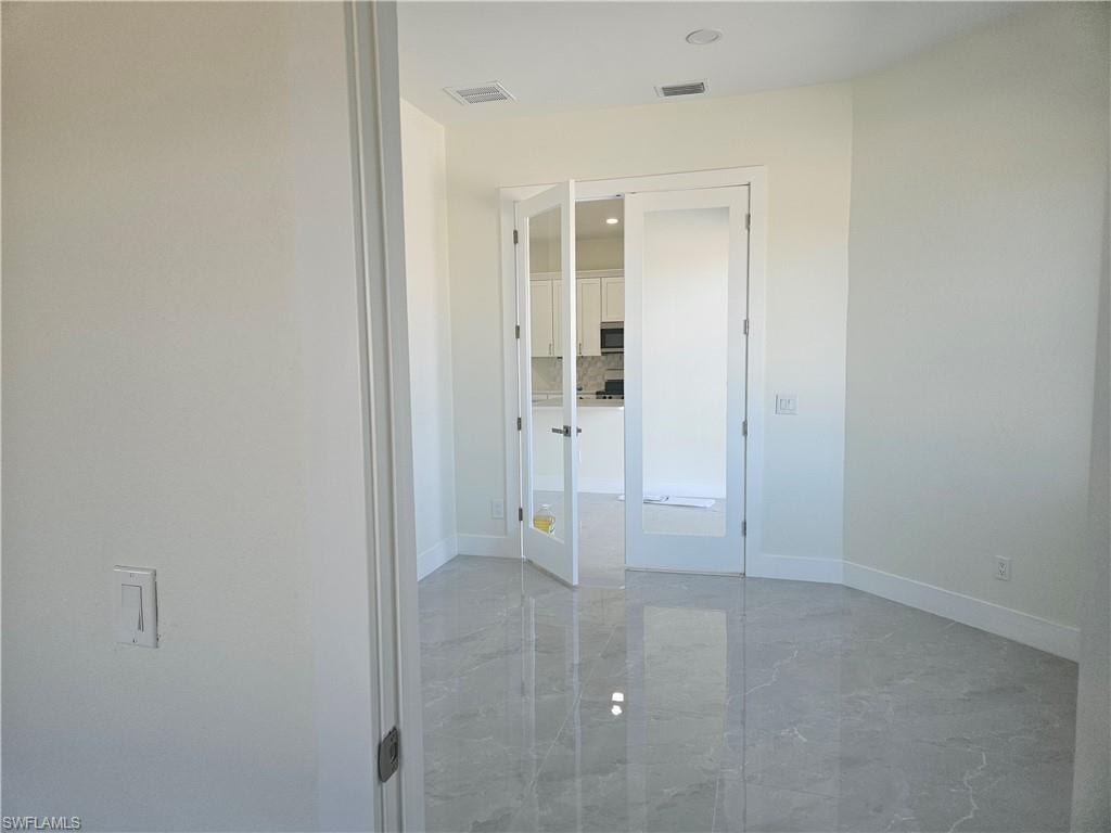 Unfurnished bedroom featuring light marble finish flooring and baseboards