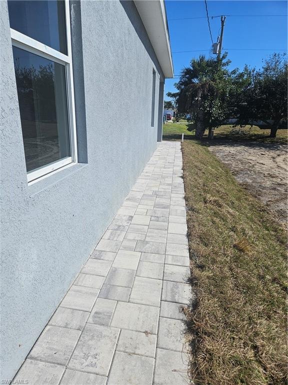 View of side of home with stucco siding and a lawn