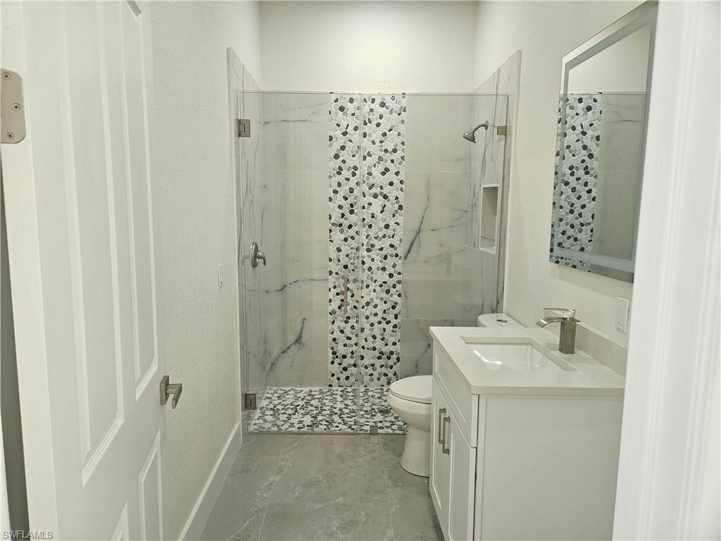 Bathroom featuring vanity, a marble finish shower, and a textured wall