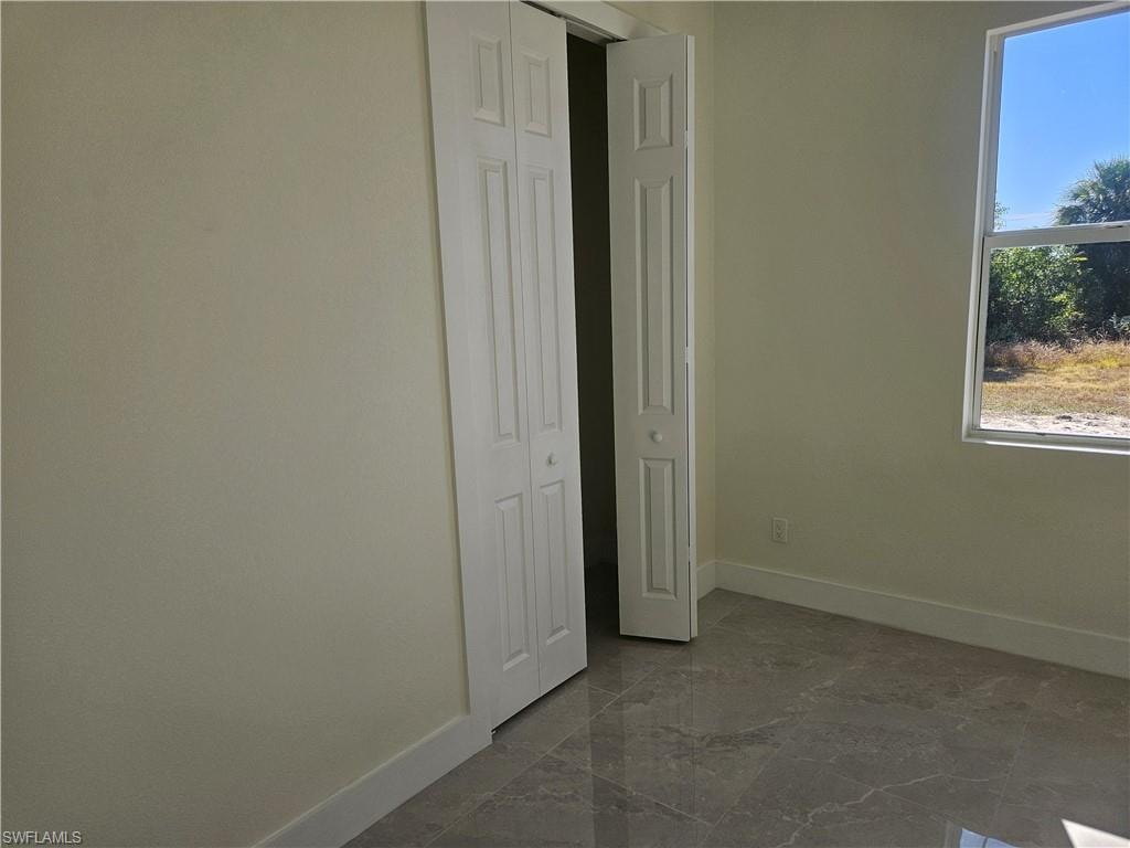 Unfurnished bedroom with dark marble finish flooring and a closet