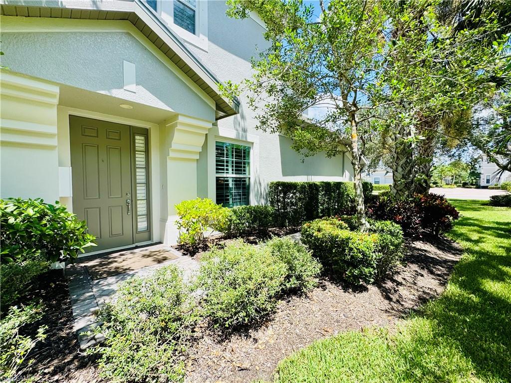 Doorway to property with stucco siding and a lawn