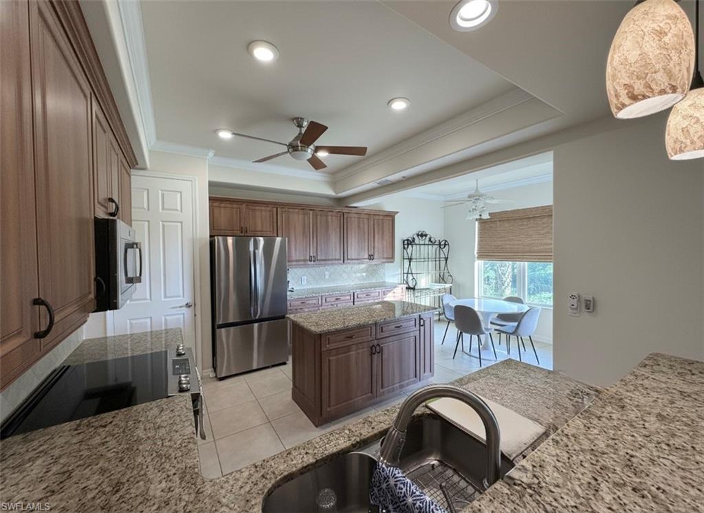Kitchen with light stone counters, ornamental molding, appliances with stainless steel finishes, a raised ceiling, and tasteful backsplash*Photos have been virtually staged for perspective.