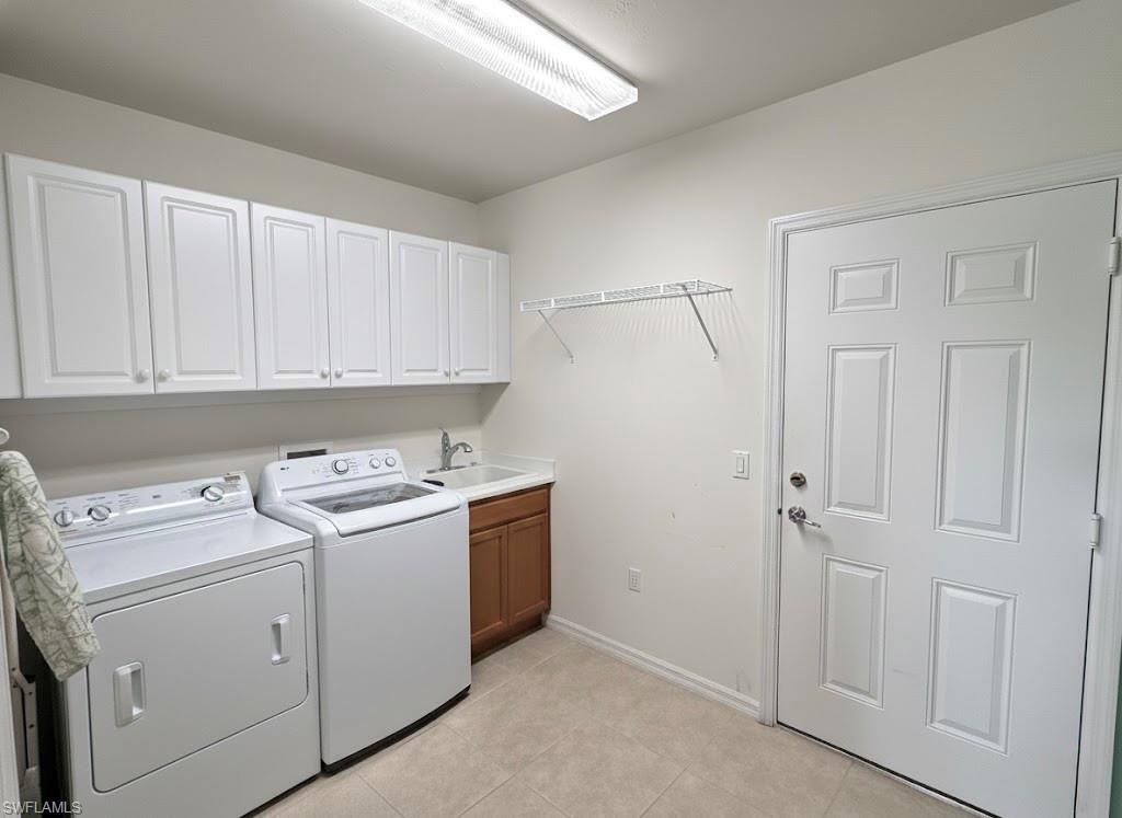 Laundry area with washer and clothes dryer, light tile patterned floors, and cabinet space