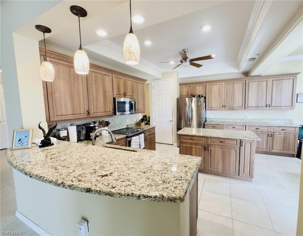 Kitchen featuring crown molding, a raised ceiling, pendant lighting, backsplash, and appliances with stainless steel finishes*Photos have been virtually staged for perspective.