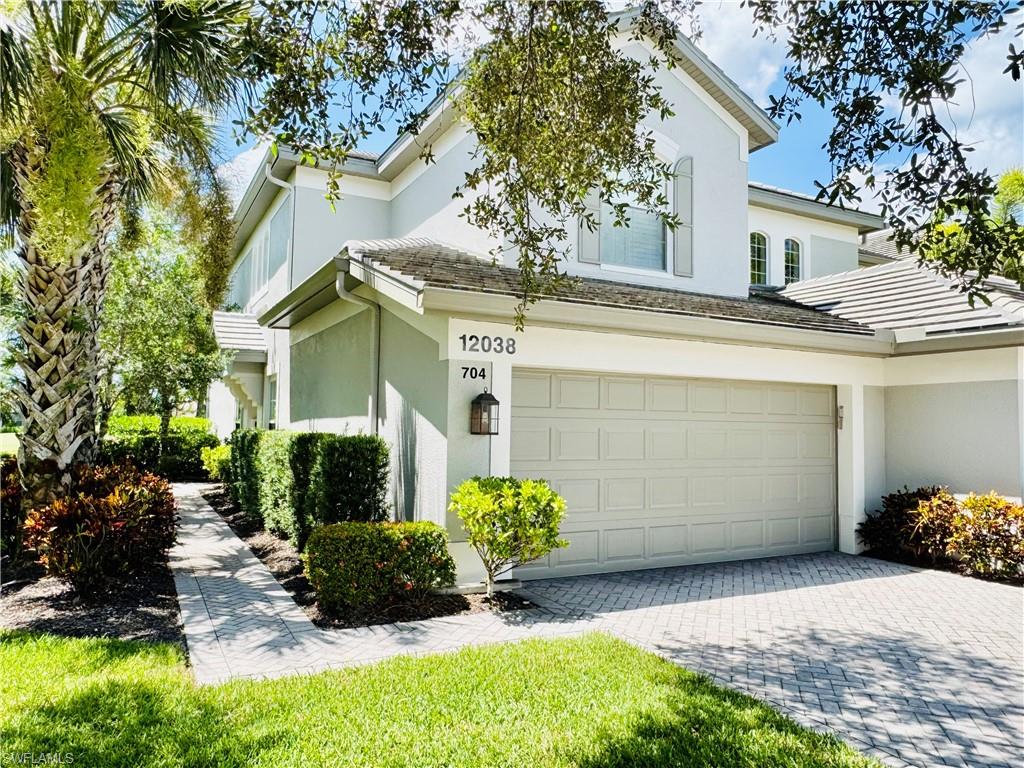 View of side of property featuring stucco siding, decorative driveway, and a garage