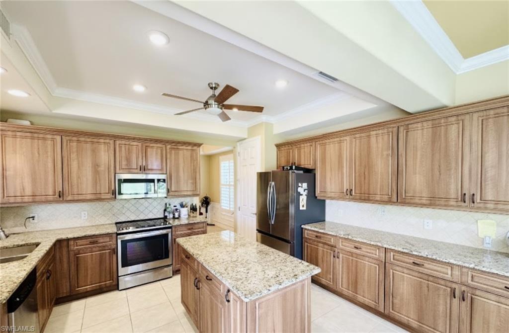 Kitchen with crown molding, a raised ceiling, appliances with stainless steel finishes, decorative backsplash, and recessed lighting*Photos have been virtually staged for perspective.