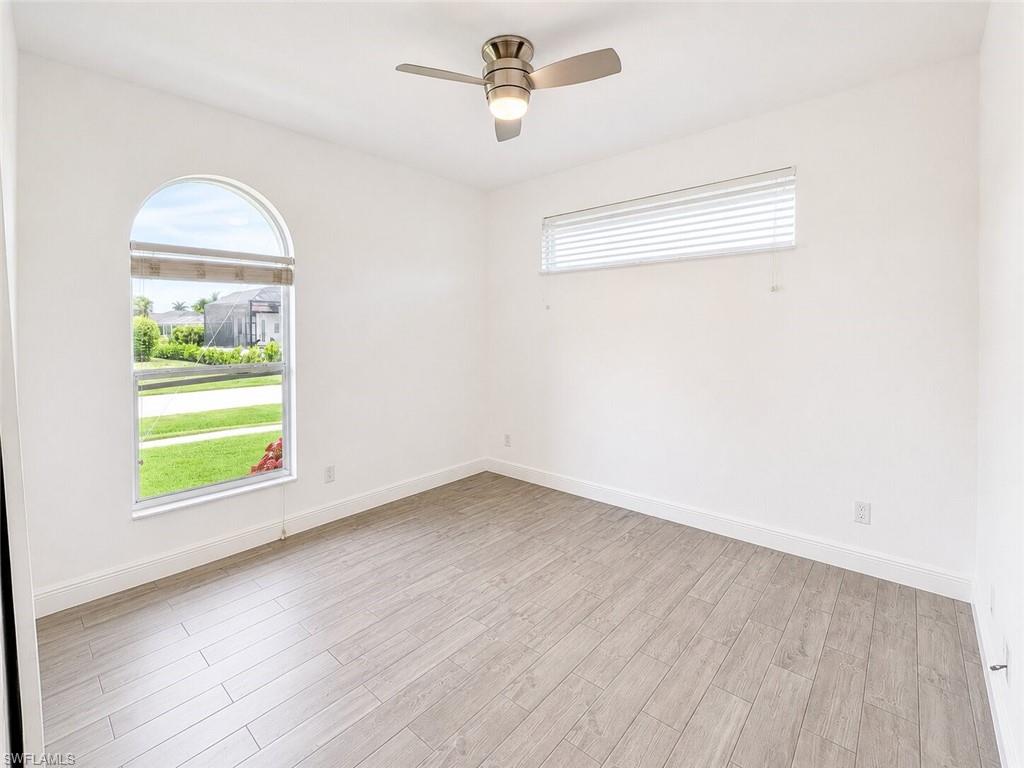 Interior room featuring a semicircular arch window with roller shade, wood-finish flooring, a contemporary ceiling fan, and white baseboards