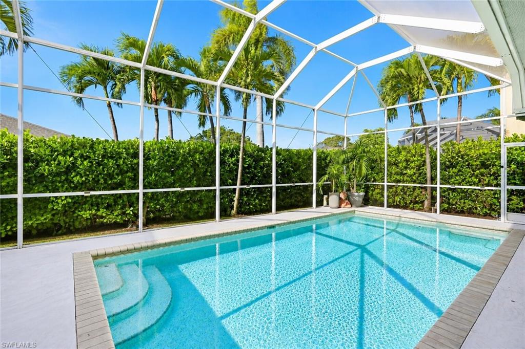 Screened-in swimming pool featuring integrated steps, paver coping, and a surrounding concrete deck