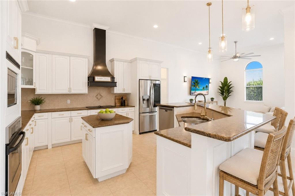 Kitchen featuring white cabinetry, a central island, stainless steel appliances, pendant lighting, and a breakfast bar with seating