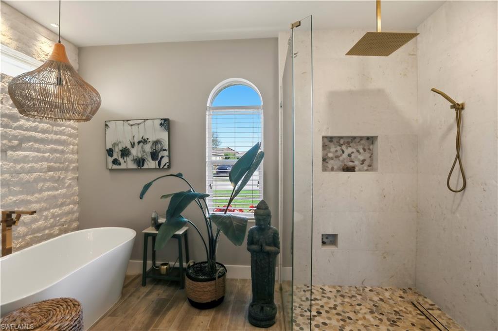 Full bathroom with a stall shower, a freestanding tub, and wood finished floors