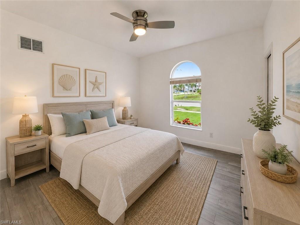Bedroom featuring an arched window, wood-finish flooring, a ceiling fan with integrated lighting, and a light-toned wooden bed frame