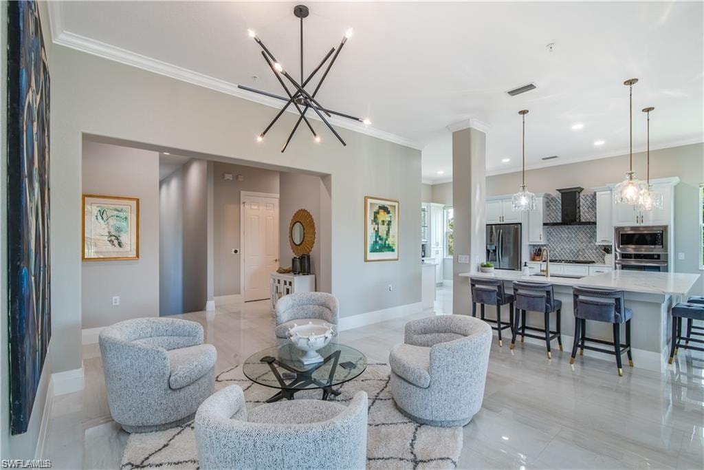 Living area featuring a chandelier, ornamental molding, and recessed lighting