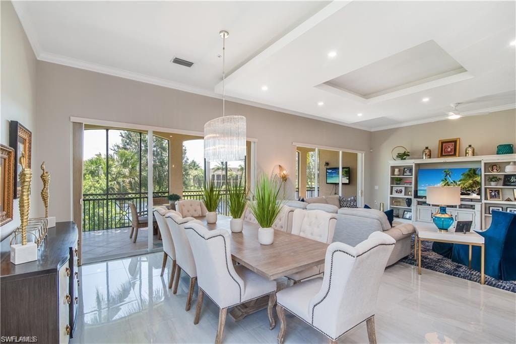 Dining room with crown molding, a chandelier, healthy amount of natural light, recessed lighting, and a raised ceiling