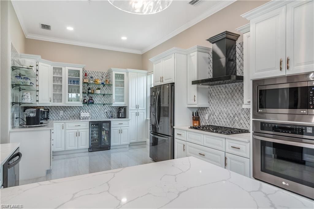 Kitchen featuring white cabinetry, stainless steel appliances, open shelves, glass insert cabinets, and wall chimney range hood