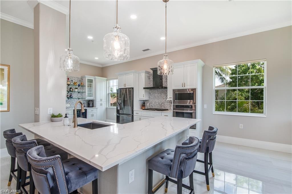 Kitchen with a kitchen breakfast bar, decorative backsplash, a peninsula, white cabinetry, and ornamental molding