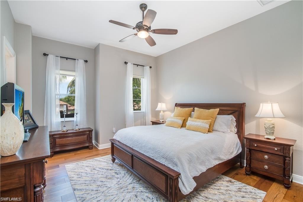 Bedroom featuring multiple windows, light wood-style flooring, and a ceiling fan