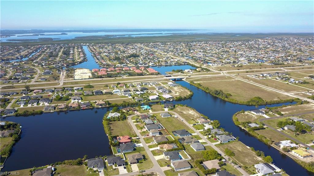 Aerial view of property and surrounding area featuring a large body of water and nearby suburban area