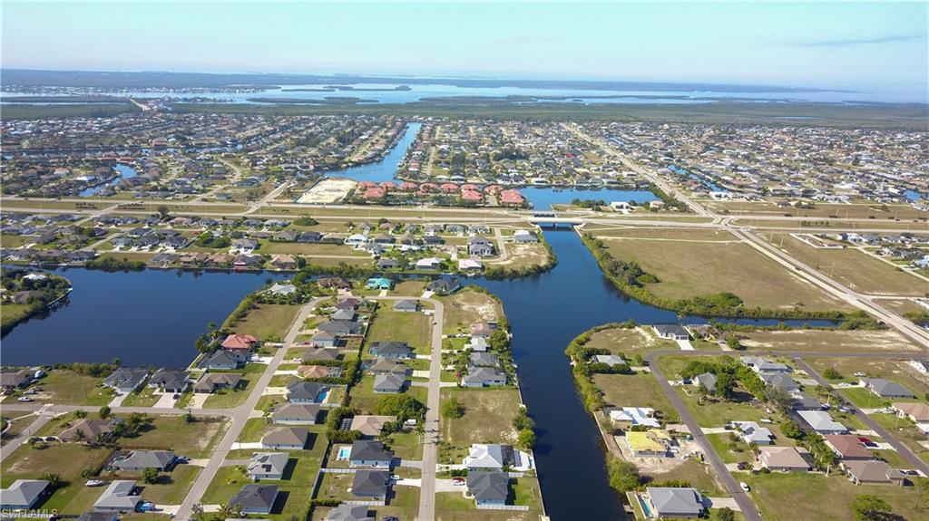 Aerial view of property and surrounding area featuring nearby suburban area and a nearby body of water