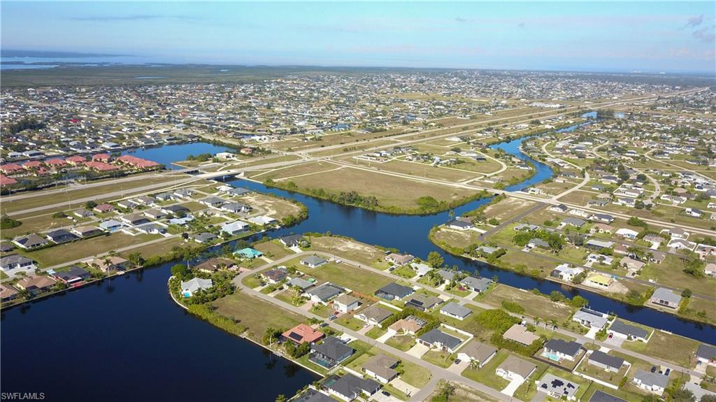 Aerial view of property and surrounding area featuring nearby suburban area and a large body of water