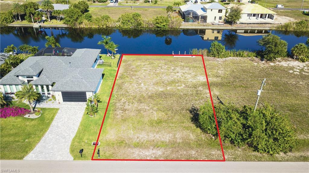 Aerial view of residential area featuring a nearby body of water and property parcel outlined