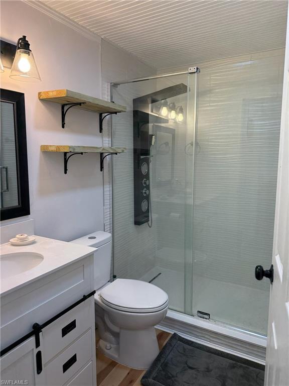 Bathroom featuring a stall shower, vanity, and wood finished floors