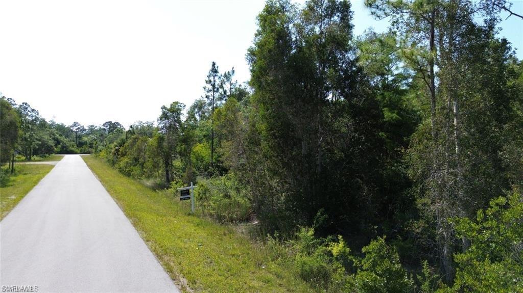 View of asphalt road featuring a wooded view