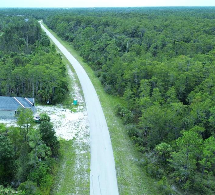 Aerial view of property and surrounding area with a forest