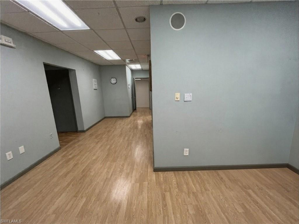Corridor featuring wood-finish flooring, drop ceiling with recessed lighting, and pale blue wall finishes