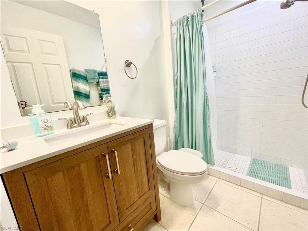 Full bath with vanity, a shower stall, and light tile patterned floors