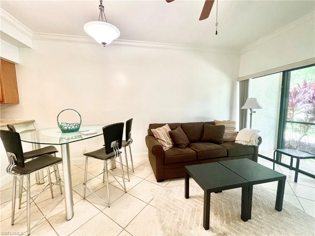 Living room featuring crown molding, light tile patterned flooring, and a ceiling fan