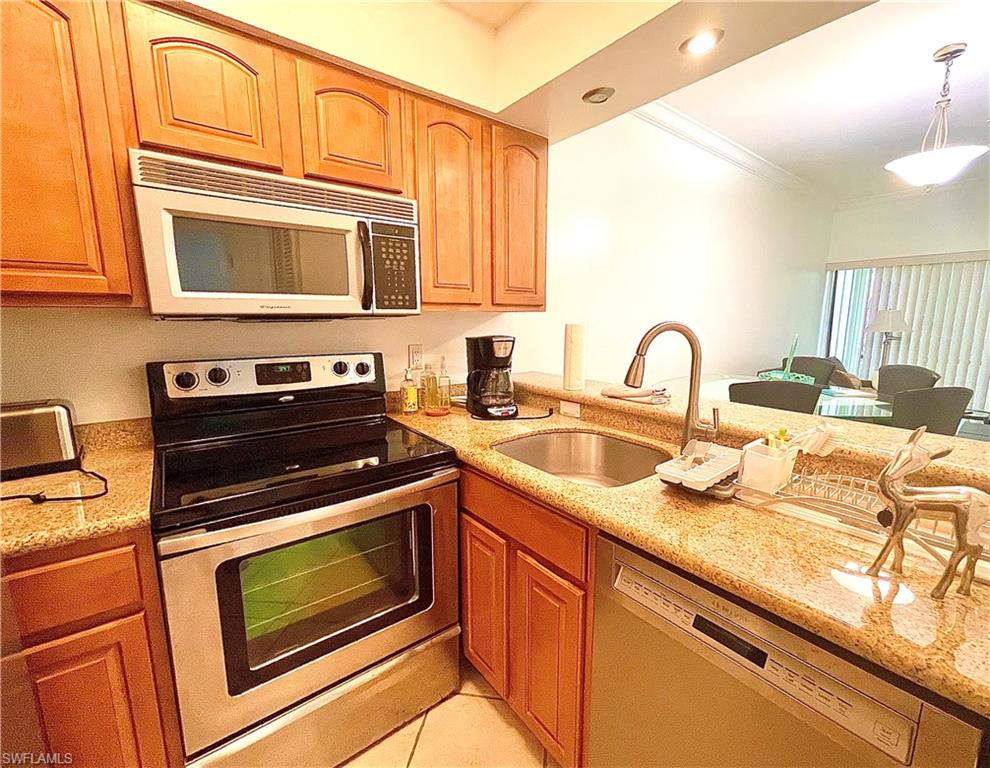 Kitchen featuring appliances with stainless steel finishes, light stone countertops, ornamental molding, pendant lighting, and recessed lighting