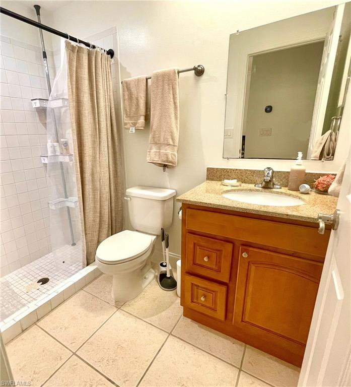Bathroom with a stall shower, vanity, and light tile patterned flooring