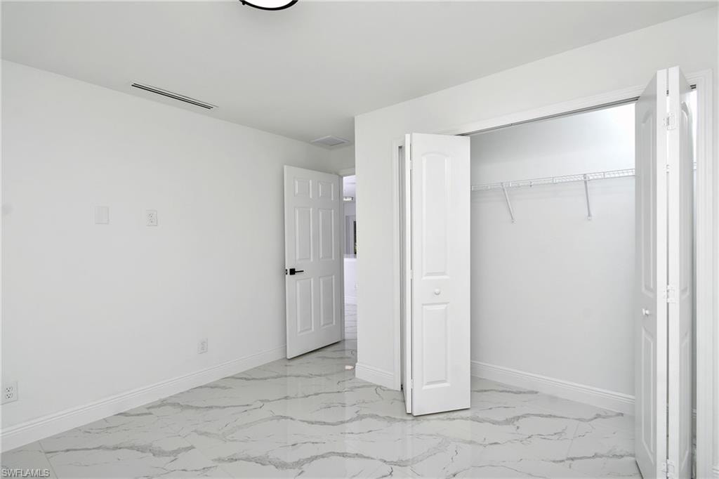 Unfurnished bedroom with light marble finish flooring and a closet