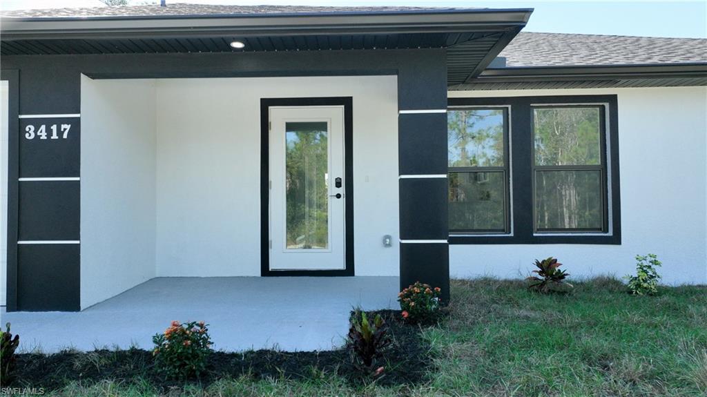 View of exterior entry featuring stucco siding and roof with shingles