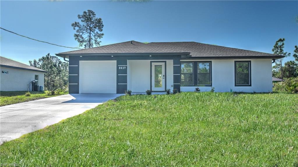 View of front facade with stucco siding, concrete driveway, a front lawn, a garage, and roof with shingles