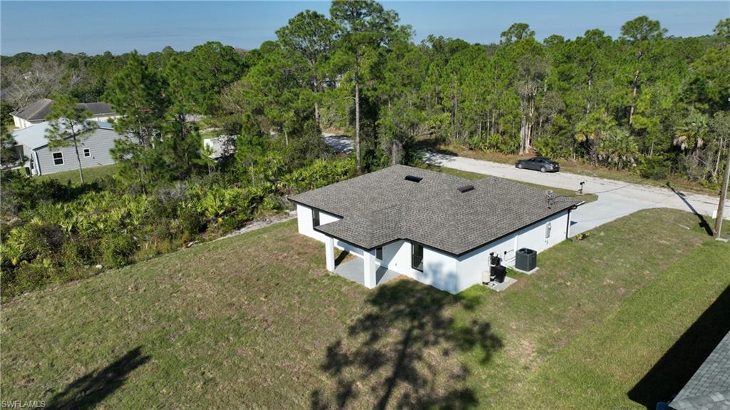Rear view of house with a lawn, a patio, stucco siding, and a shingled roof