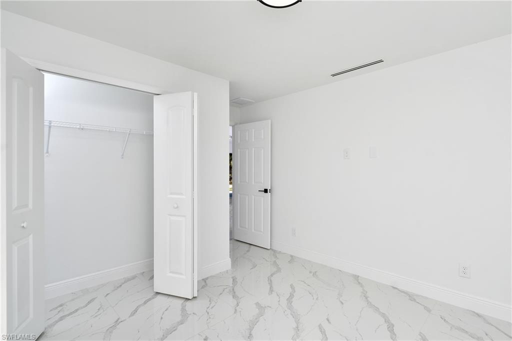Unfurnished bedroom with a closet and light marble finish floors