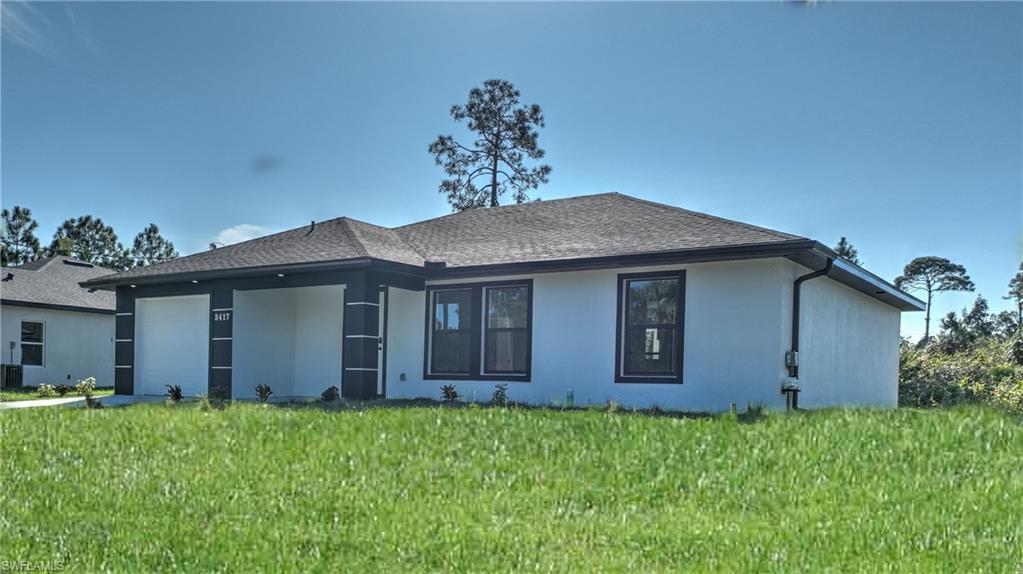 Back of house featuring a garage, stucco siding, a lawn, and a shingled roof