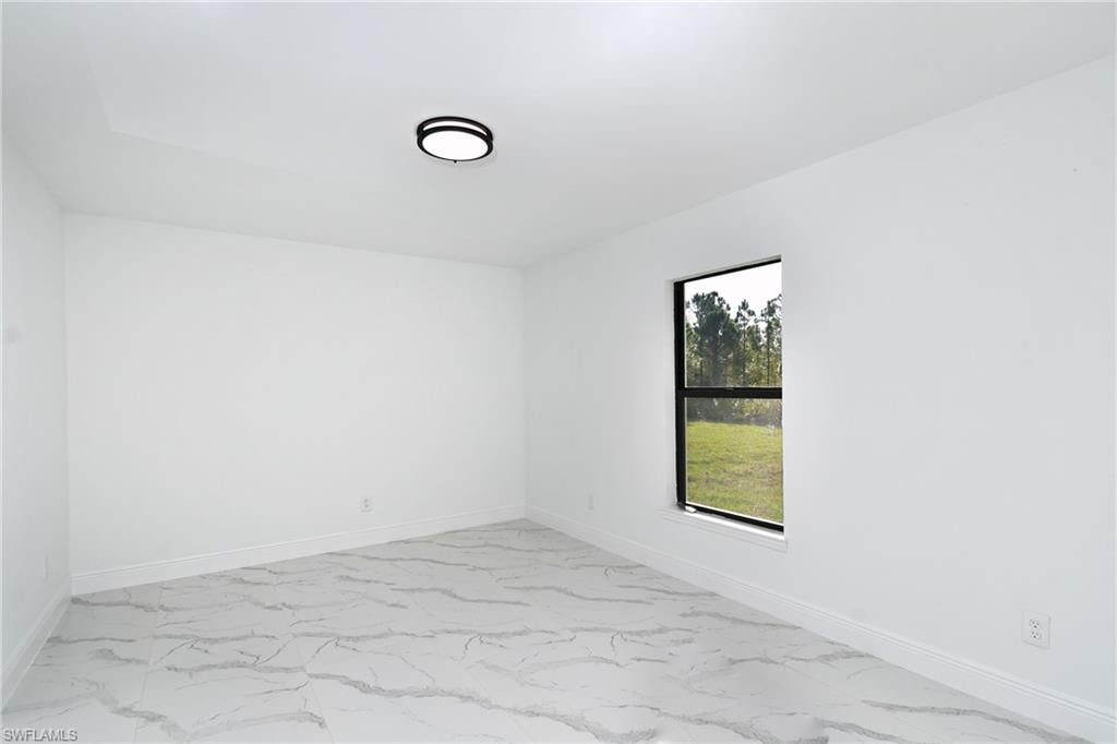 Unfurnished room featuring light marble finish floors and baseboards