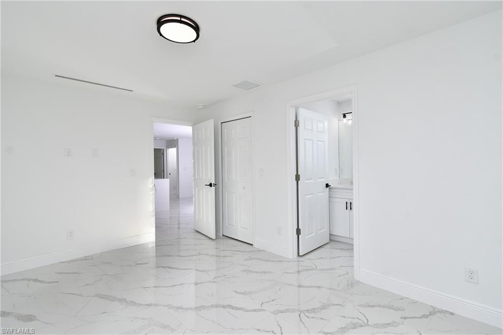 Unfurnished bedroom with light marble finish flooring, a closet, and ensuite bath