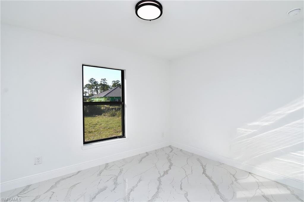Empty room with baseboards and marble look tiles