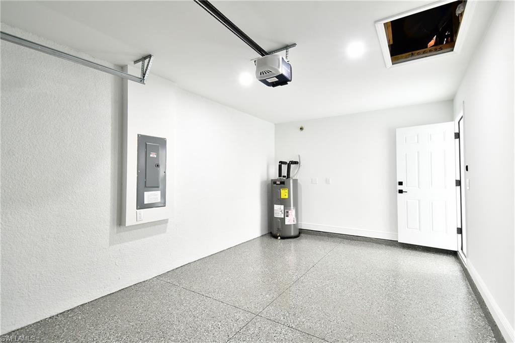 Garage with electric panel, a garage door opener, and electric water heater