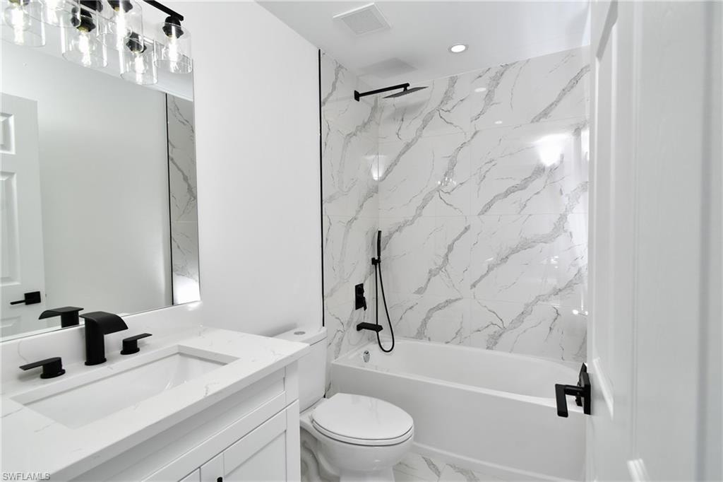 Bathroom featuring vanity, a combined bath / shower with marble appearance, and marble finish flooring