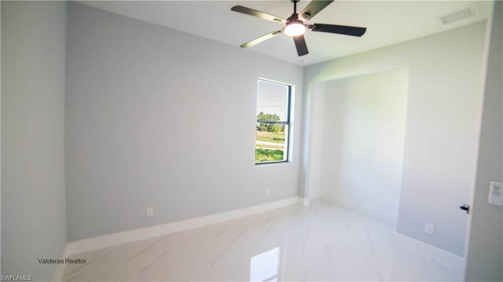 Unfurnished room with light marble finish flooring and a ceiling fan