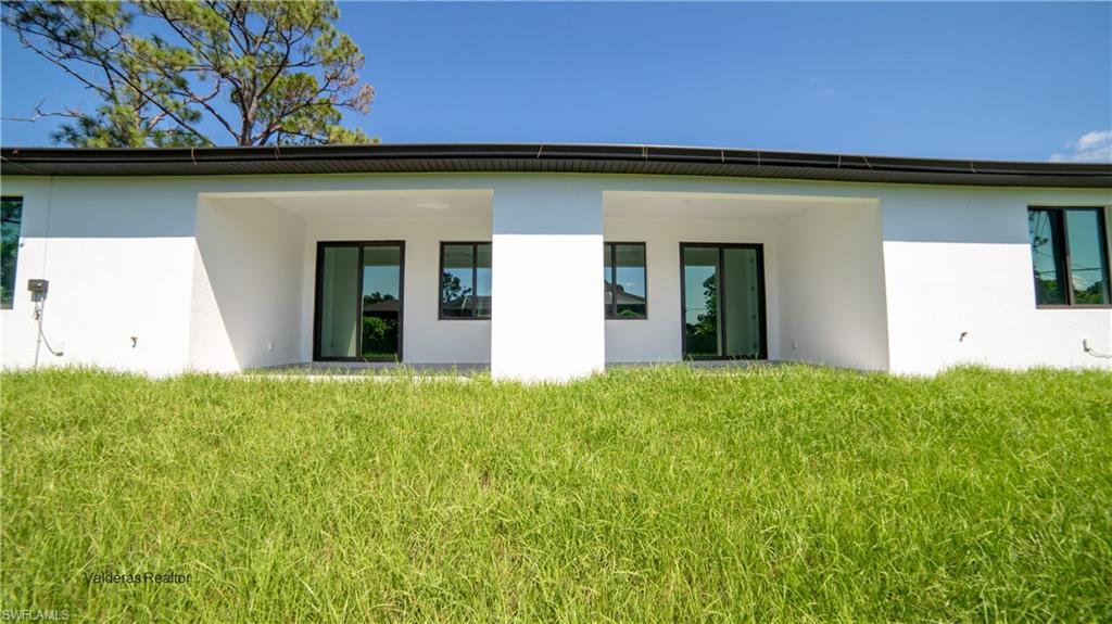 Rear view of house featuring stucco siding, a yard, and a patio area