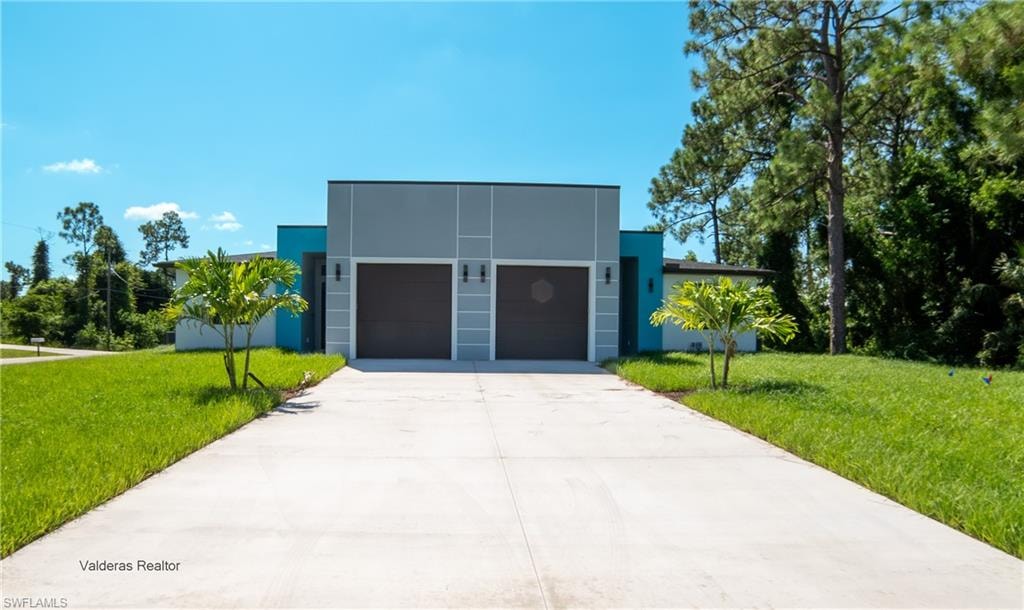 View of front facade featuring stucco siding, a front yard, driveway, and a garage